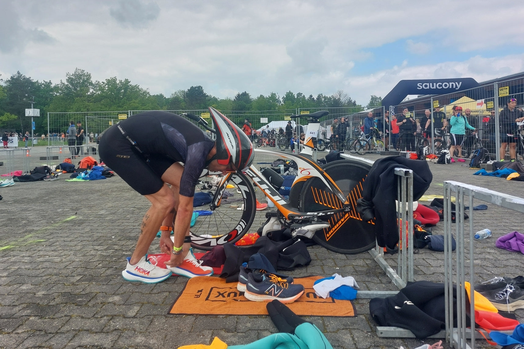 Ein Triathlet in der Wechselzone hat sein Fahrrad abgestellt und schlüpft in seine Laufschuhe